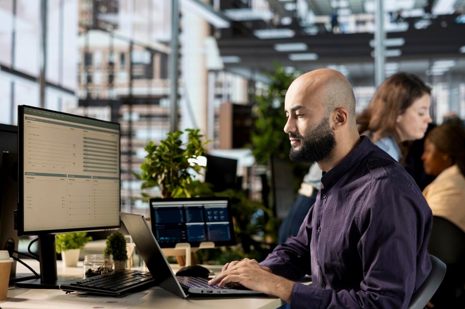 A man at a desk with a laptop and monitors, showcasing IT Support For Small Companies in Asheville, NC, and secured IT solutions.