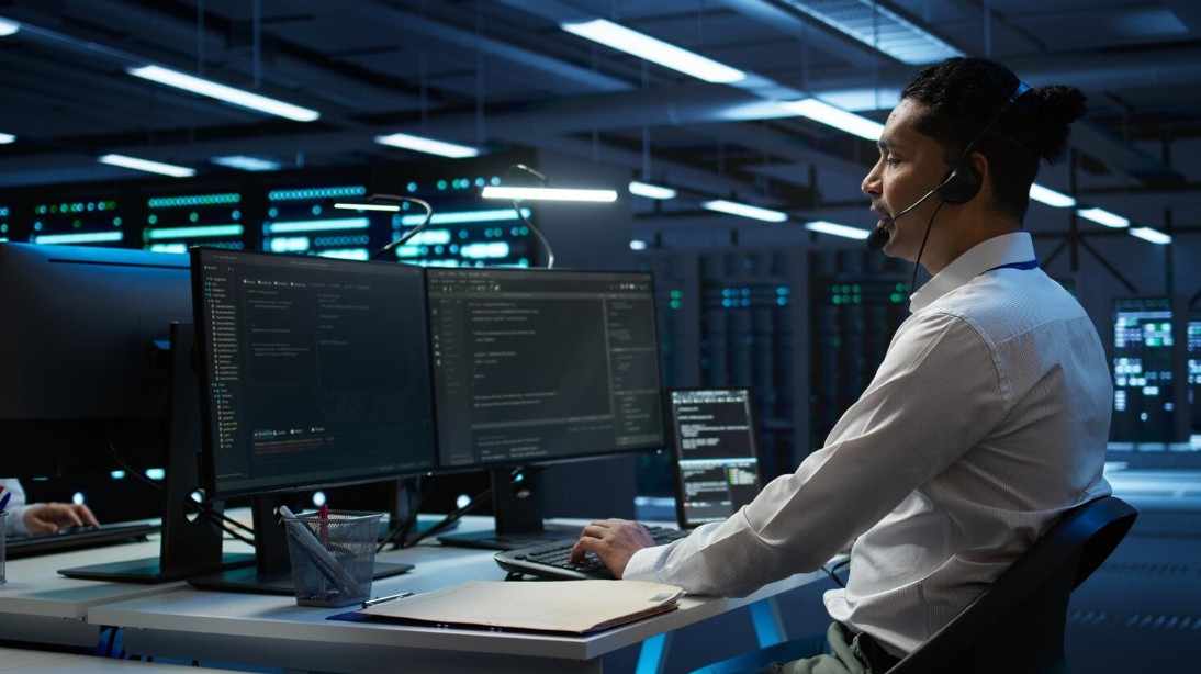 A man in a white shirt at a desk with two monitors, showcasing Managed IT Services For Small Businesses in Greenville, SC.