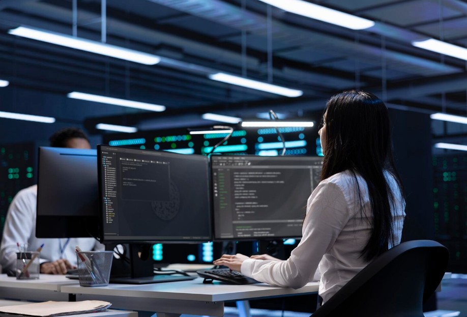 Woman at desk with two monitors, representing IT Support Company in Asheville, providing secured IT solutions and cybersecurity.